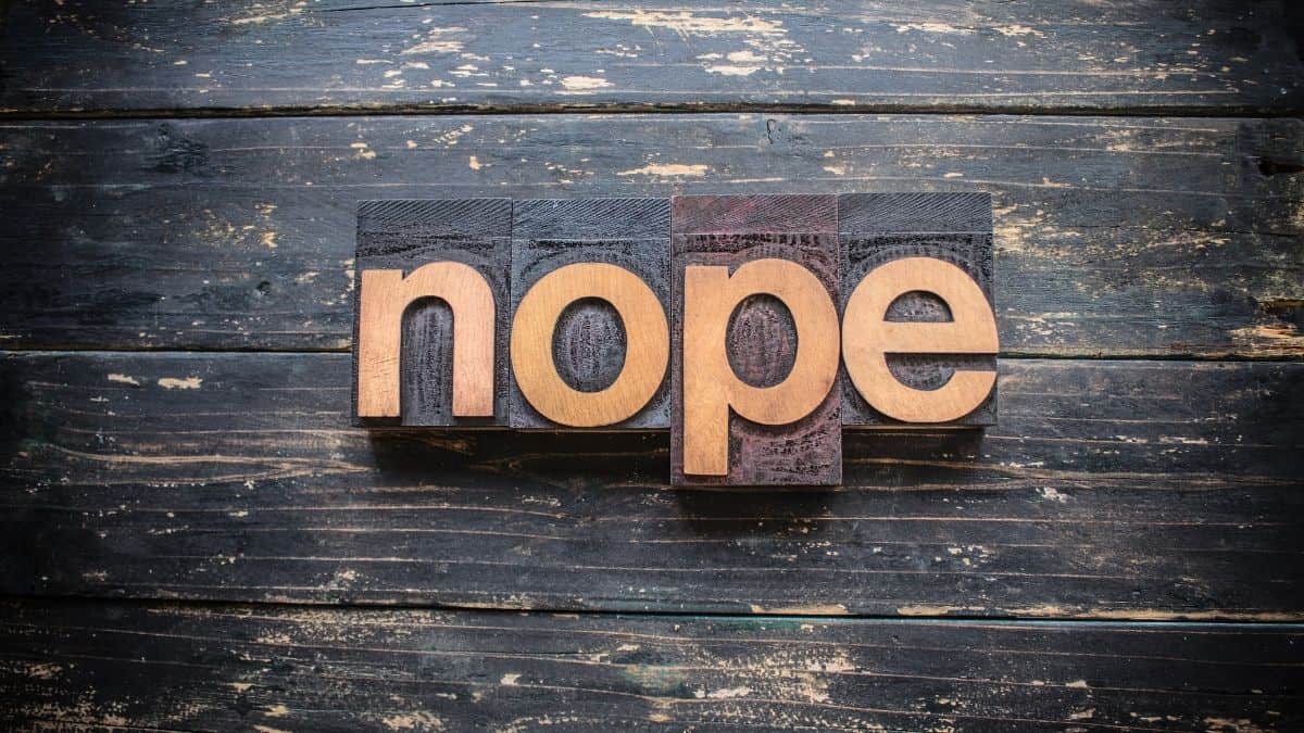 _nope_ spelled out in wooden blocks on a dark wood table.