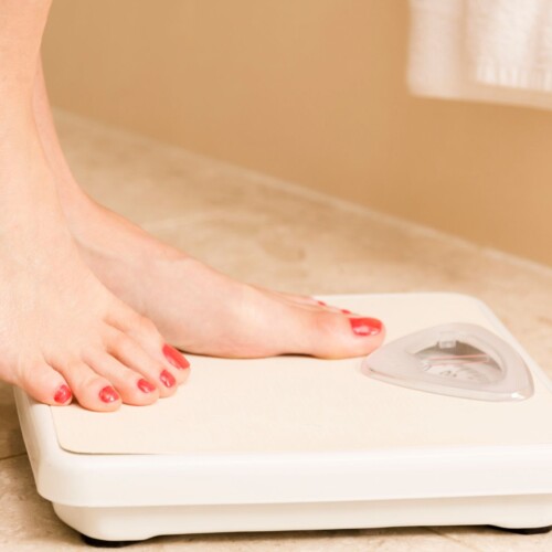 Stepping on a scale with fear of weight gain.