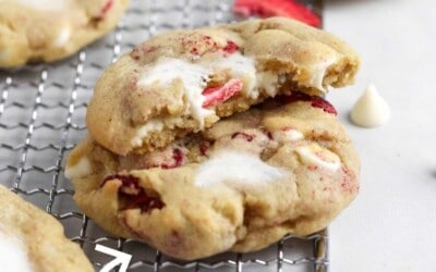 A stack of strawberry cookies with cheesecake filling. The text overlay reads: strawberry cheesecake cookies only 25 minutes.