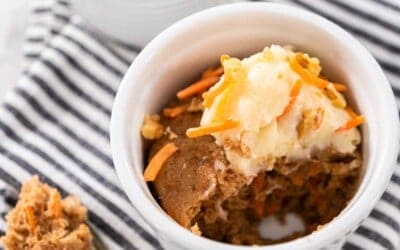 Two mugs of carrot cake, with a portion taking out with a spoon.