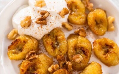 A plate of banana slices, topped with whipped cream and nuts.