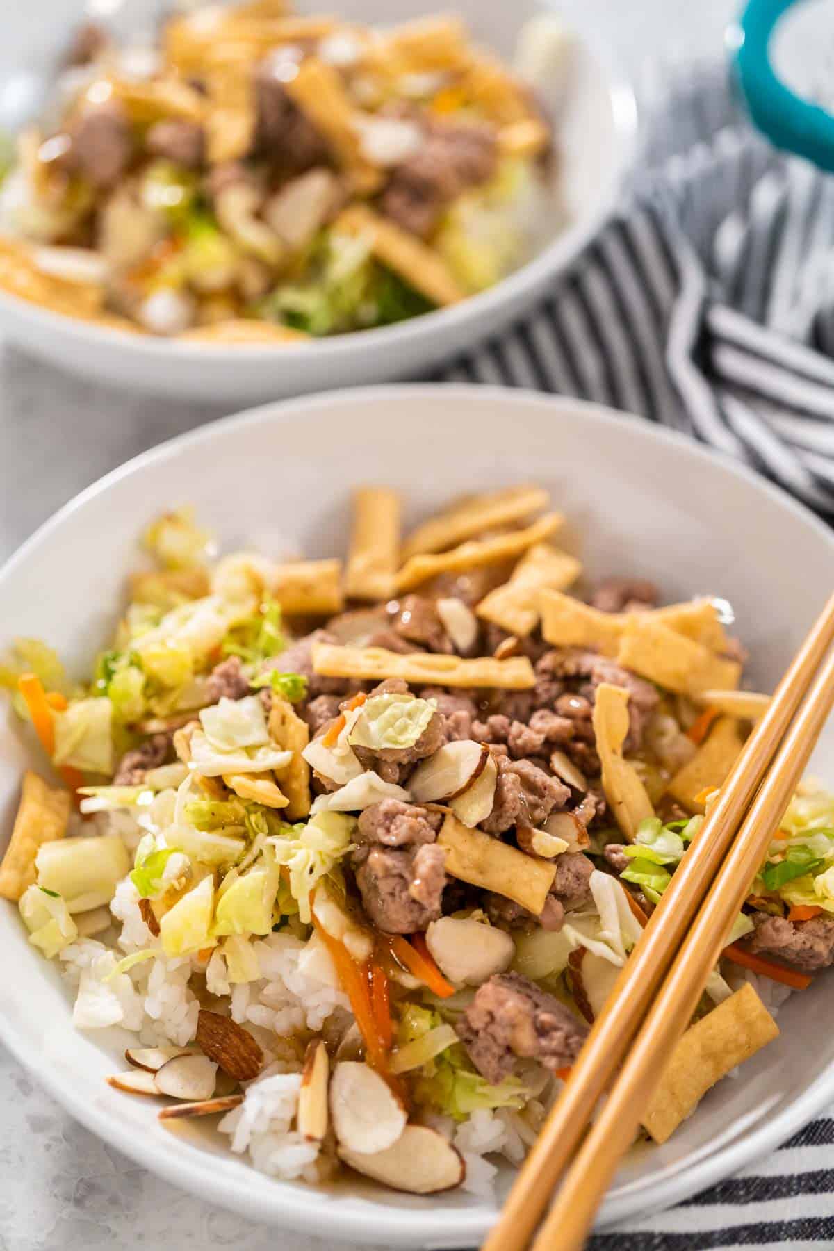 A bowl of rice, shredded cabbage, carrots, and ground meat.