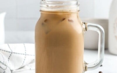 A large mug of iced coffee with a stainless straw.