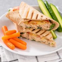 A tuna melt wrap cut in half, served with vegetables on the side.
