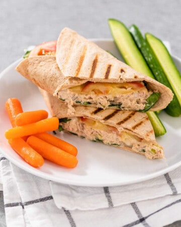 A tuna melt wrap cut in half, served with vegetables on the side.