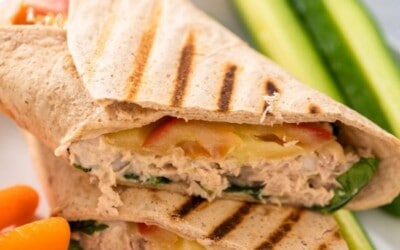 A tuna melt wrap cut in half on the diagonal and served with vegetables.