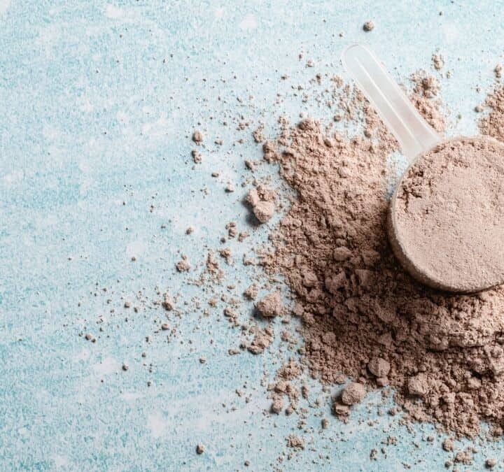 scoop of protein powder on blue table.