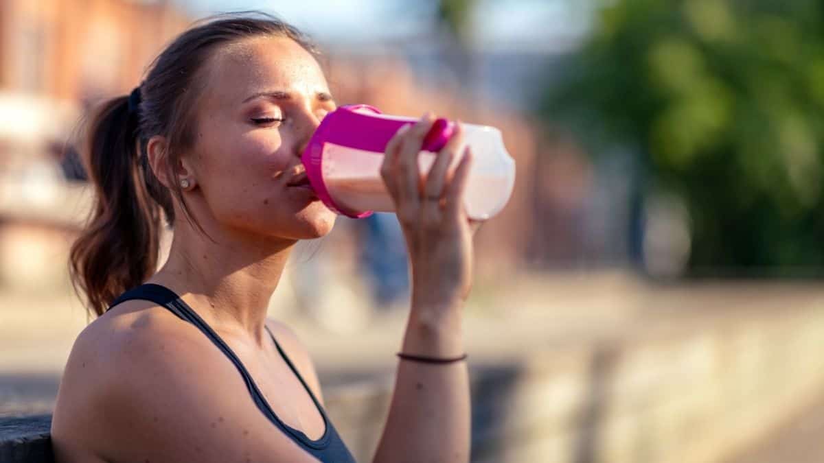 women outside drinking protein shake.