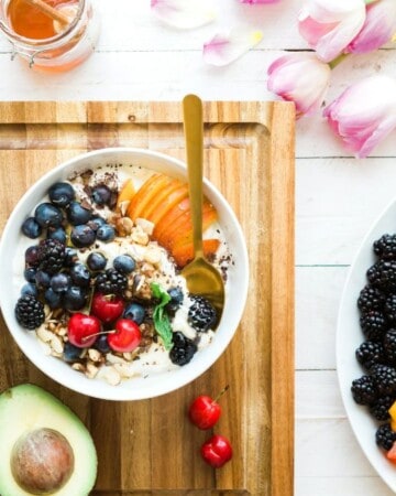 a smoothie bowl topped with fresh fruit and a coffee.