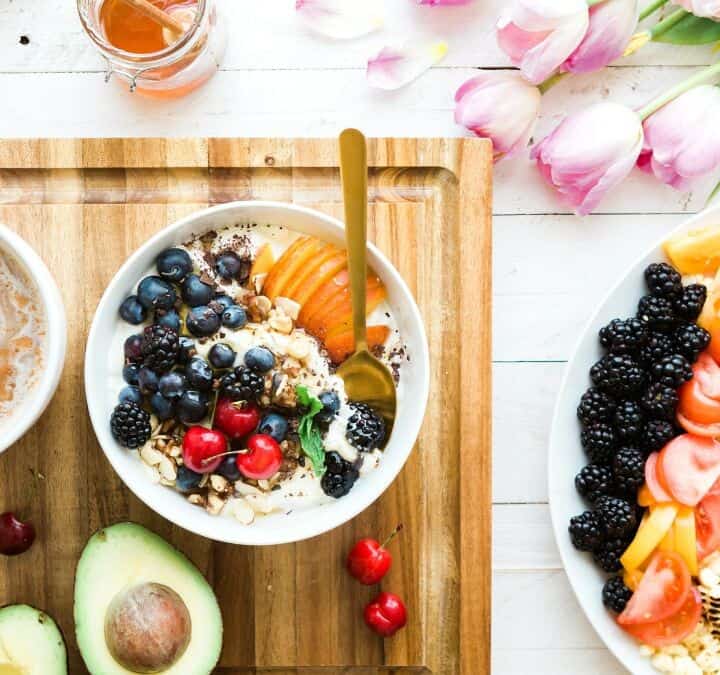 a smoothie bowl topped with fresh fruit and a coffee.