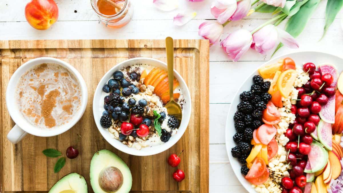 a smoothie bowl topped with fresh fruit and a coffee.