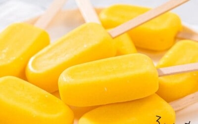 A pile of homemade mango popsicles on a plate.