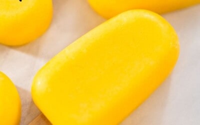 A mango popsicle, surrounded by others, with a text overlay that reads: mango pops, 2 ingredients.
