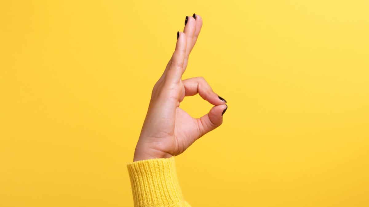 hand holding ok sign with yellow background.