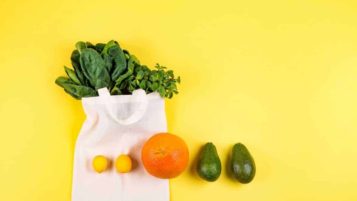 fruits and vegetables in a white sack on a yellow background.