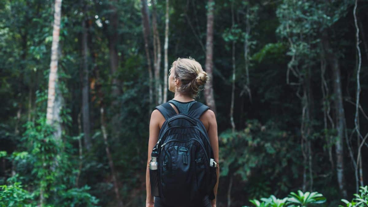 women with backpack about to start journey in forest.