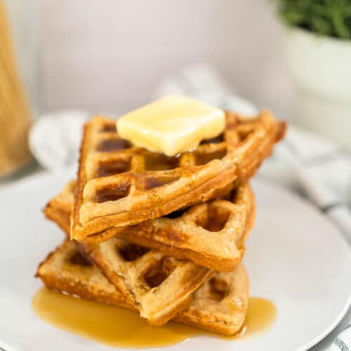 Stack of four Oat Flour Waffles with a pat of butter and syrup on top.