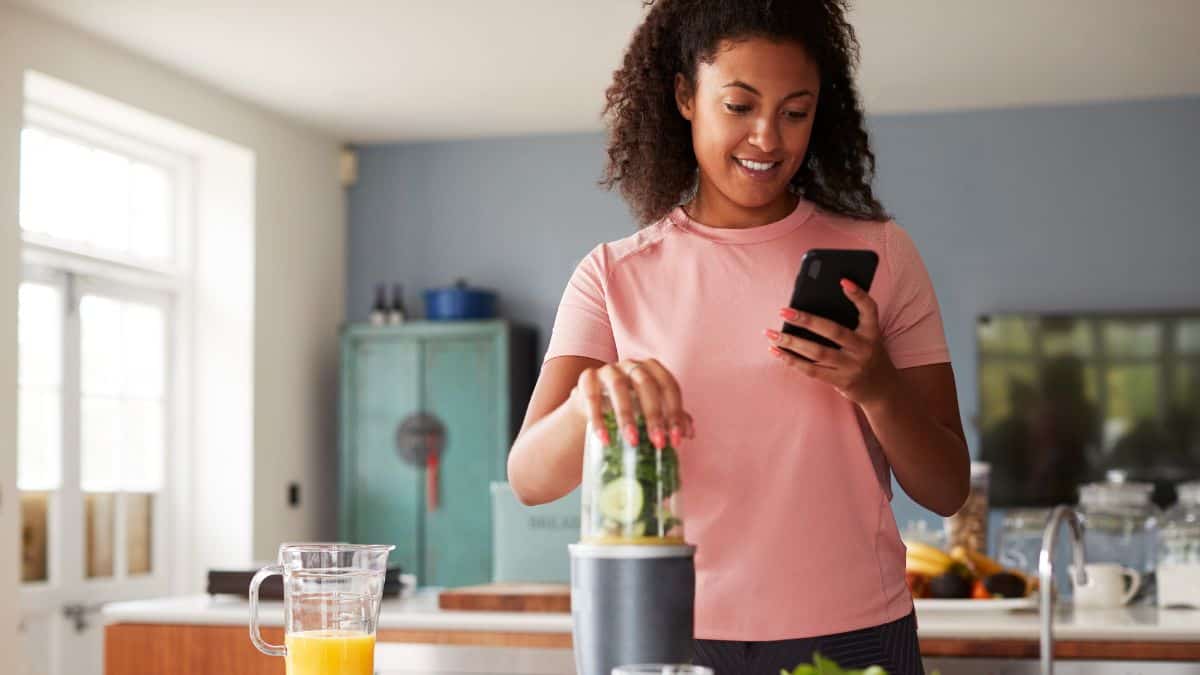 a woman with pink nail polis tracking calories on her phone app.