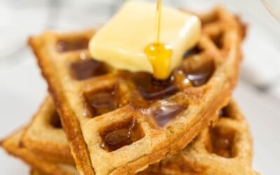 Syrup being poured onto a stack of waffle corners.