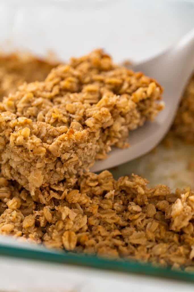 Lifting a square of baked oats from a pan.