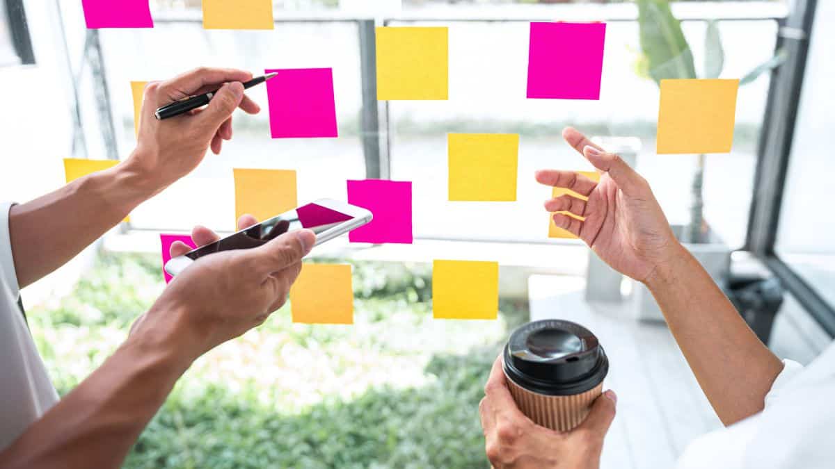 a group of people working on a paper schematic on a window with colorful post-it notes.