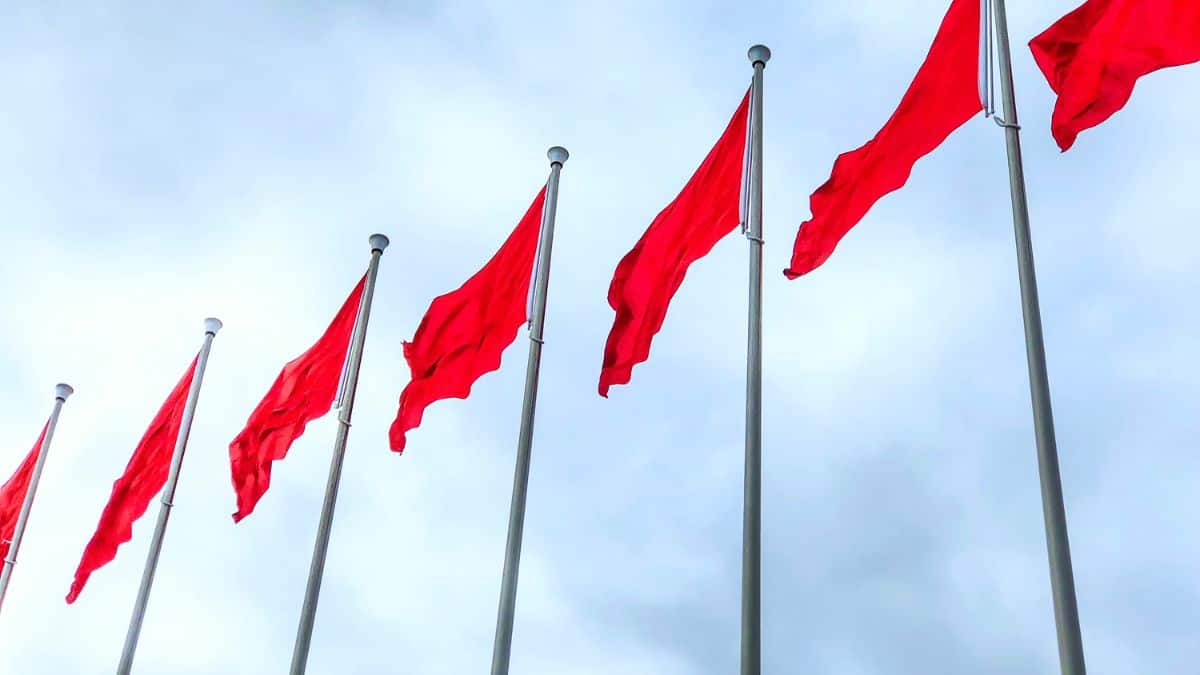 7 big red flags waving on sunny day.