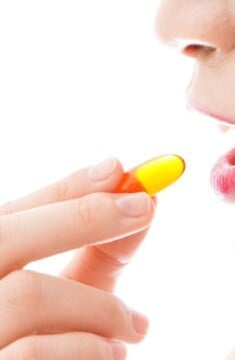 A close view of a woman putting an oval pill in her mouth, similar to plexus.