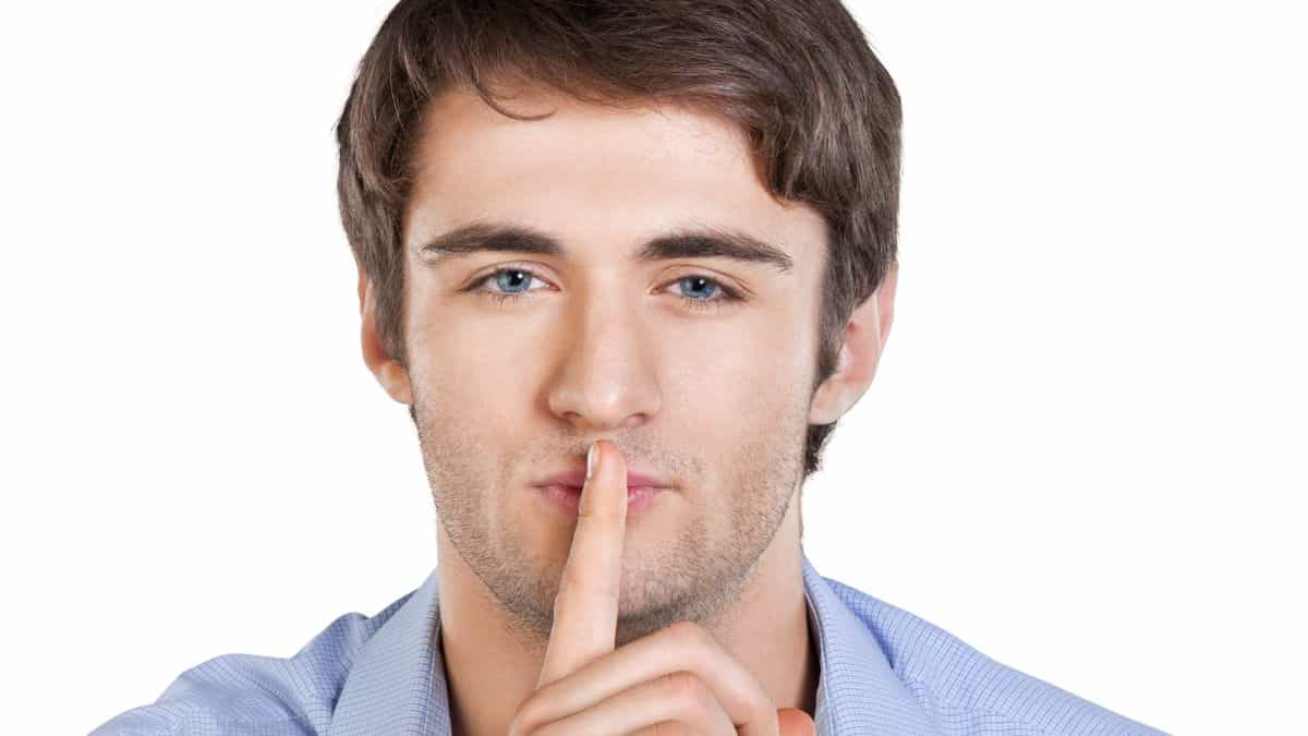 man with a secret holding index finger to his mouth.