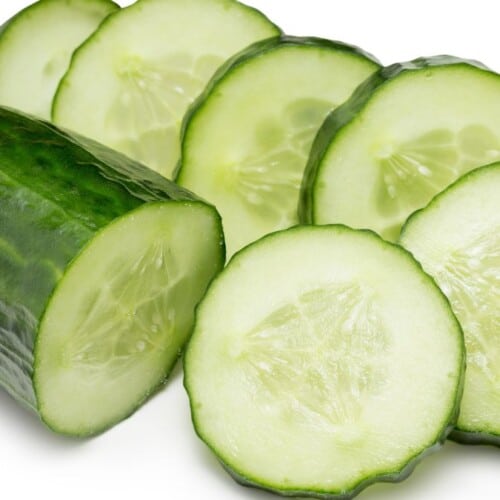 half of a cucumber and slices on white background.