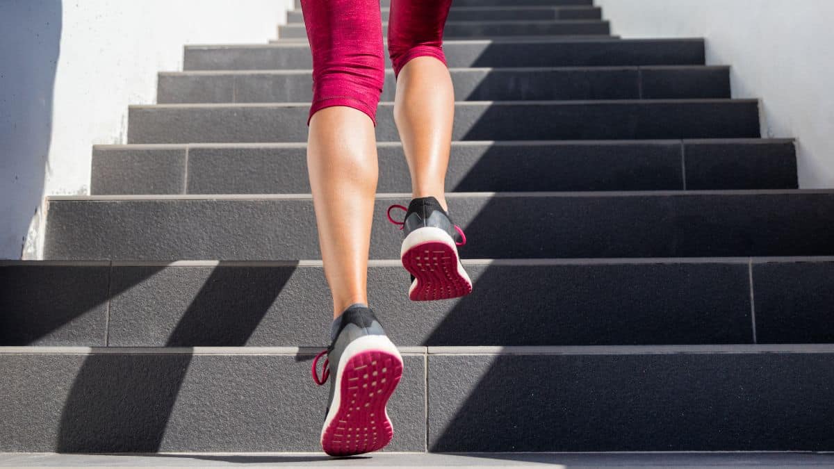 person in pink shoes and leggings climbing up gray stairs.
