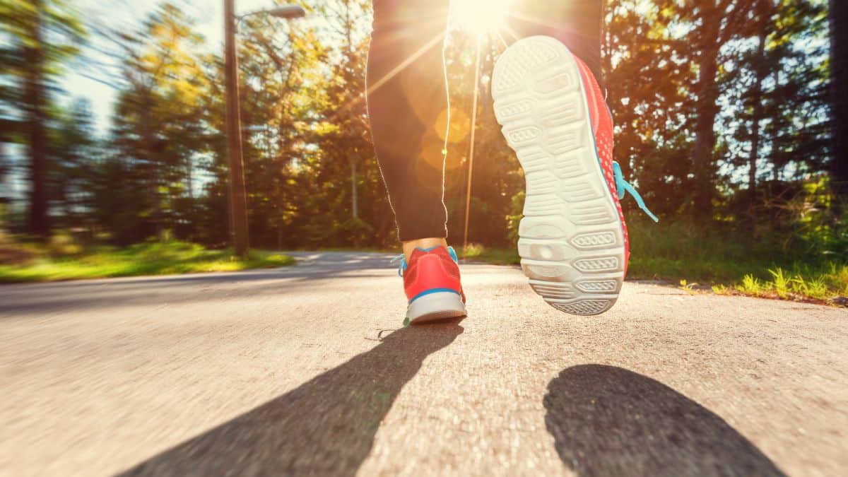 A close up showing a woman’s sneakers as she jogs down a street.
