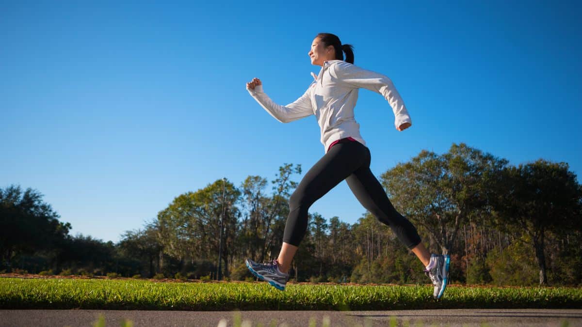 a woman running on a path on a sunny day.